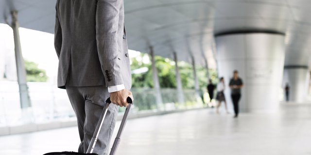 Photo of a businessman walking while holding a suitcase